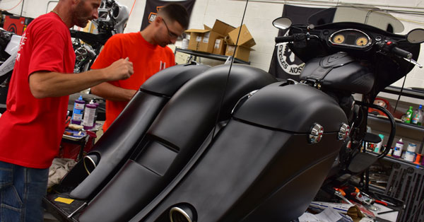 picture of a hydro dipped customization for an indian motorcycle that is matte black, picture of splashed hydrographics professionals working on a indian motorcycle customization, water transfer printing