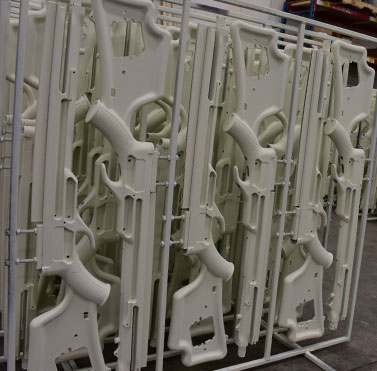 hydrographics, picture of a rack of weapons that are white and about to get camouflage hydrographics put onto them